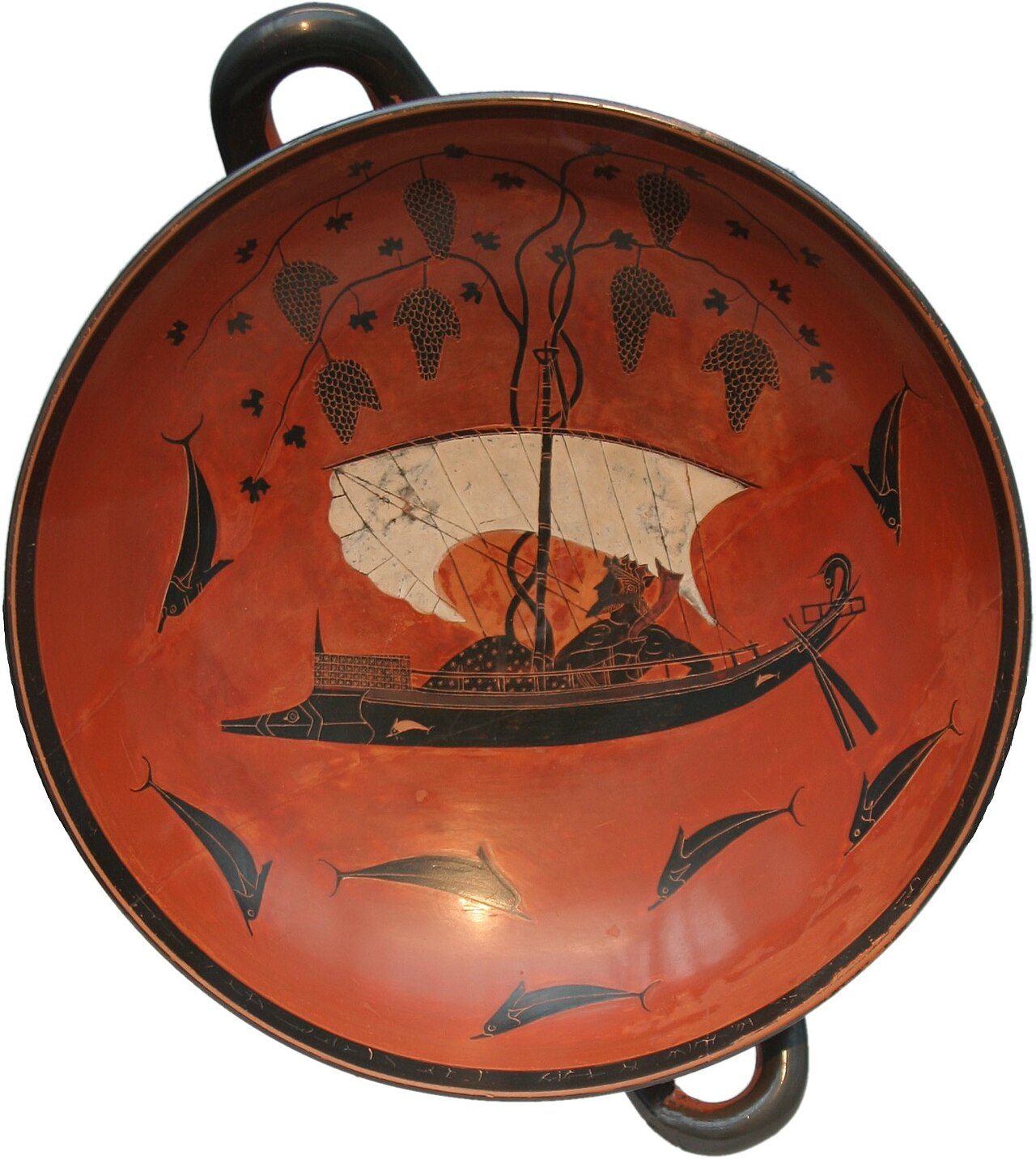 The interior of a black-figure kylix by the vase painter Exekias, circa 530 BC, showing Dionysus reclining in a sailboat whose mast has become a grapevine heavy with clusters of grapes, surrounded by leaping dolphins.