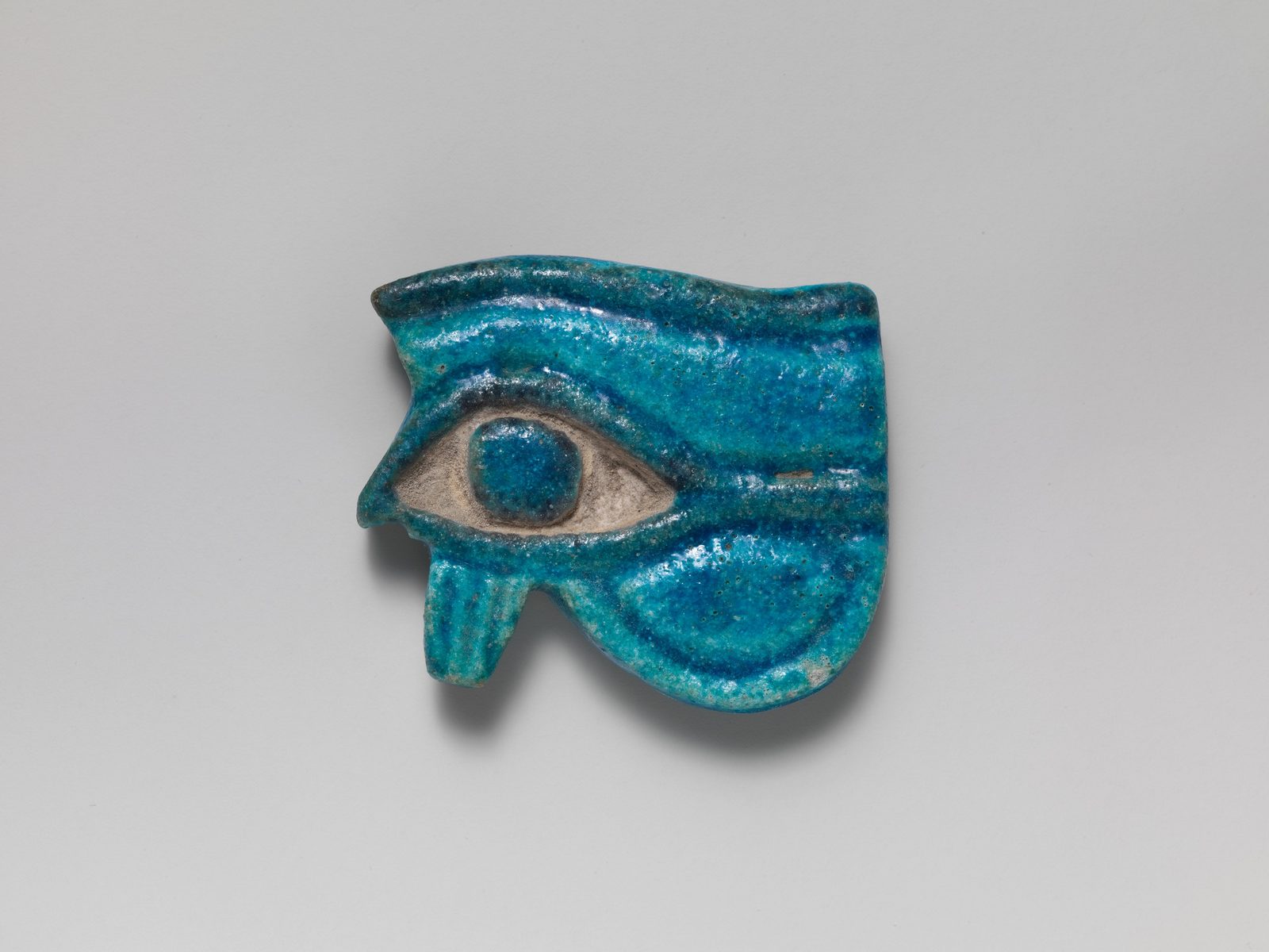 Small blue-glazed faience Wedjat-eye amulet from ancient Egypt, dated circa 1090-900 BC, from the Metropolitan Museum of Art's Cesnola Collection.