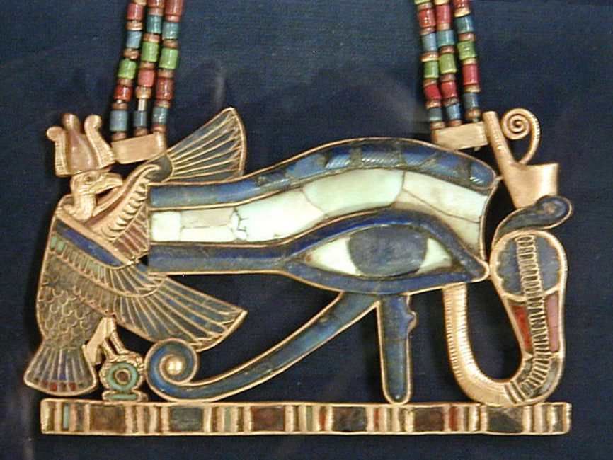 A gold and faience Wedjat eye pendant in the classic Eye of Ra form, combining a human eye with the facial markings of a falcon.