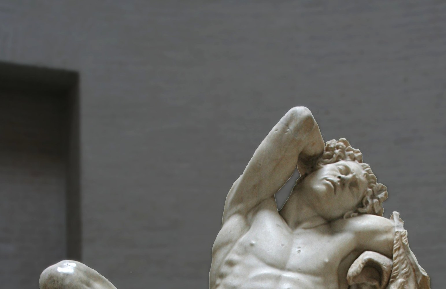 The Barberini Faun, a Hellenistic marble statue of a sleeping male figure with an entirely human body and no goat features, reclining on a rock in the Glyptothek museum in Munich.