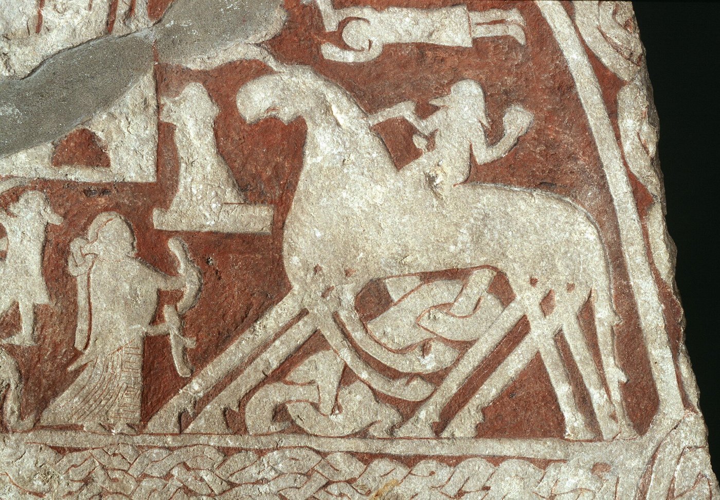 A carved and painted Viking Age picture stone from Tjängvide, Gotland, showing a rider on an eight-legged horse, with a figure holding a cup and a smaller figure to the left.
